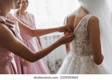 the bride, with her girlfriends in matching pink dresses, in the morning, help the bride get ready for the wedding ceremony - Powered by Shutterstock