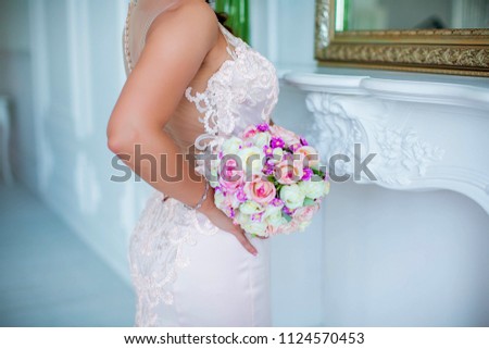 Bride holding wedding bouquet in hands, near waist, closeup
