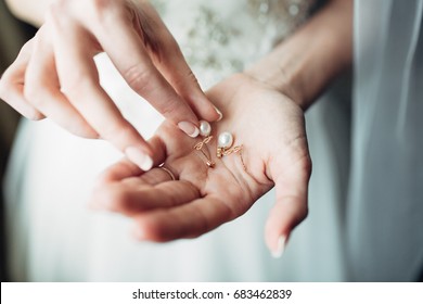 Bride Holds Pearl Earring In Her Fingers