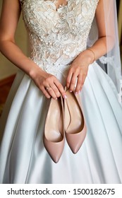 Bride holds the wedding beige shoes in her hands.