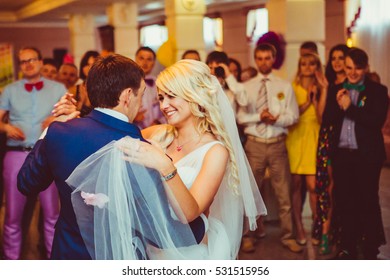 Bride Lies Her Hand Over Groom's Shoulder While Dancing In The Crowd Of Happy Friends