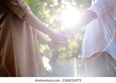 A bride and a man holding hands in a sunlit outdoor ceremony.