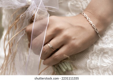 bride with a modern gold bracelet, wedding ring and solitaire ring on her wrist,  holding elegant modern autumn wedding bouquet.The concept of lifestyle and autumn wedding