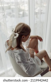 Bride morning. A girl in a white peignoir sits on a chair. Glamorous photo shoot by the window.