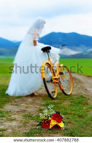 bride on orange bike in beautiful wedding dress with lace in landscape. with wedding bouquet. wedding concept