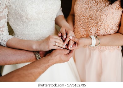 Bride On Wedding Day Holding Her Mother's And Father's Hands. Concept Of Relationship Between Mom, Dad, Daughter. The Mother And Father Of The Bride Bless The Bride For A Happy Family Life. Close Up.