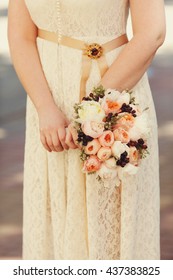Bride in peach dress holds a wedding bouquet of pink flowers - Shutterstock ID 437383825