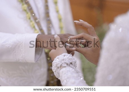 the bride pins the wedding ring on the groom's finger