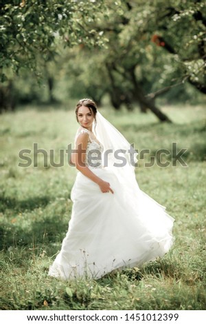 bride posing in a green park; girl in a white dress on a background of green
