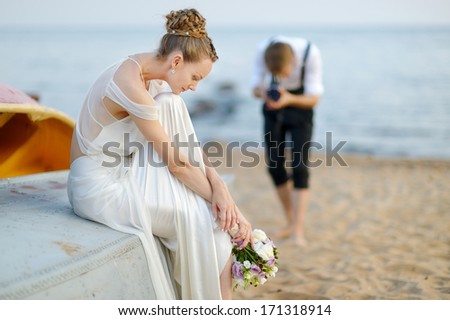 Bride posing for her groom while shooting with an old camera