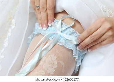 Bride preparing for wedding, putting on a blue lace garter 