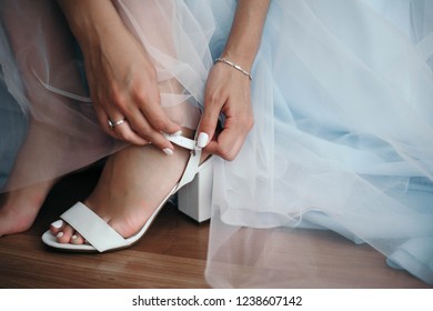 Bride puts on she's white shoes. Attractive woman's legs  and beautiful bridal dress. - Shutterstock ID 1238607142