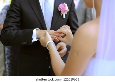 bride puts wedding ring on groom's finger