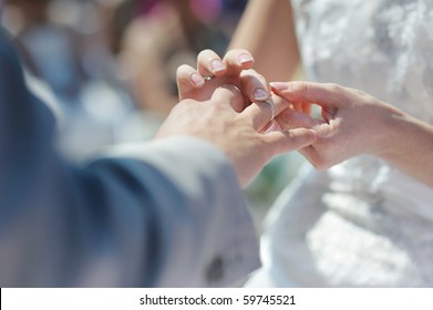 Bride Putting A Wedding Ring On Groom's Finger