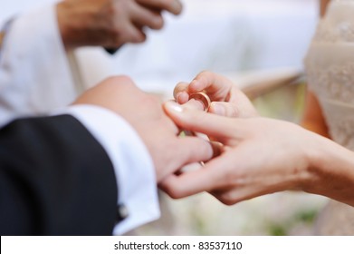 Bride Putting A Wedding Ring On Groom's Finger