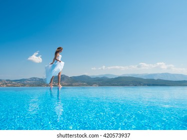 Bride Standing On The Edge On The Infinity Pool In Santorini Greece