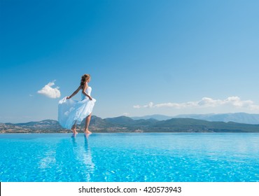 Bride Standing On The Edge On The Infinity Pool In Santorini Greece