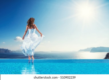 Bride Standing On The Edge On The Infinity Pool In Santorini Greece