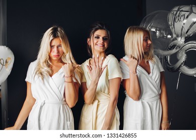 Bride Standing With Sad Bridesmaids And Showing Wedding Rind