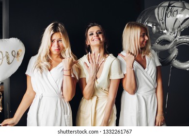 Bride Standing With Sad Bridesmaids And Showing Wedding Rind