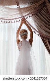 The bride stands at the window.