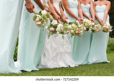 Bride surrounded by bridesmaids in mint dresses holding flowers