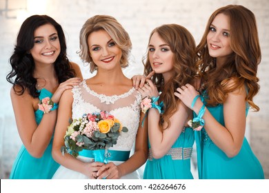 Bride And Three Bridesmaids In Similar Blue Dresses With Perfect Make Up And Hair Style In A Light Loft Space