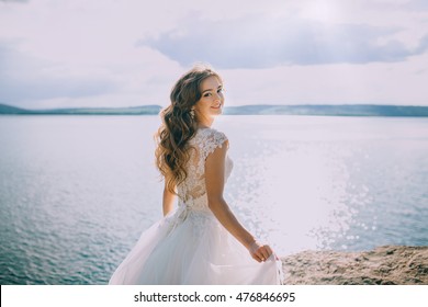 Bride Walking Along Lake Coast Wearing Beautiful Wedding Dress