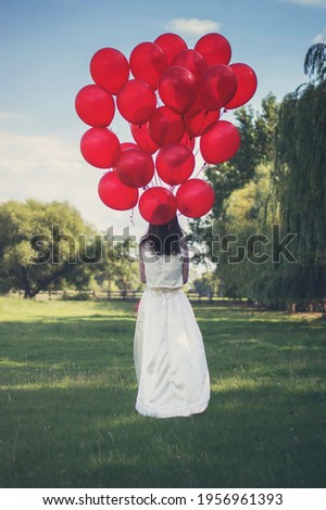 Bride walking away with a bouquet of red balloons