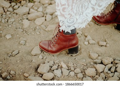 A Bride Wearing Leather Boots While Hiking On A Rocky Dirt Road In Her Wedding Dress During Her Adventure Wedding Elopement Day Near Denver, Colorado.