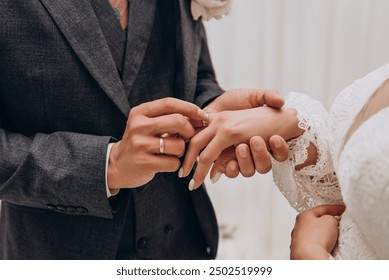 The bride wears a wedding ring to the groom at the wedding ceremony.
Hand in hand. Wedding, holiday, engagement.