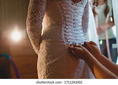 
bride in a wedding dress. bridesmaids lace up a corset on the bride