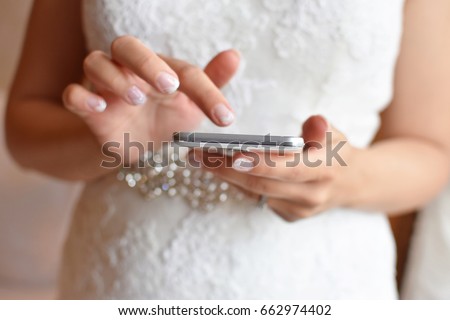 Bride in wedding dress holding smartphone in hands