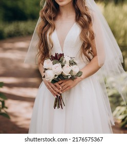 the bride in a wedding dress holds in her hands a beautiful wedding bouquet of white, cream, green roses, peonies, eustomas and green eucalyptus leaves.Autumn bouquet of flowers. - Shutterstock ID 2176575367