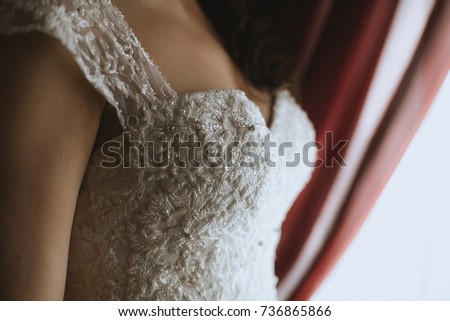 A bride in the wedding dress near the window 