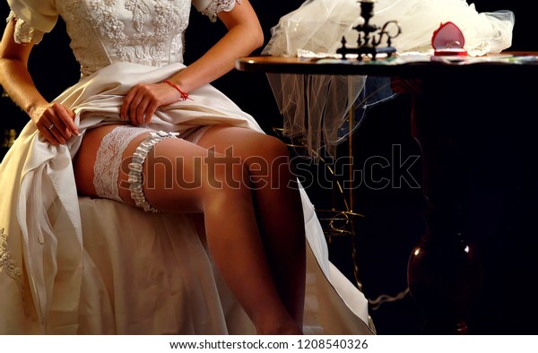 Bride wedding garter. Wedding night preparing\
garter. Bride undressing and put veil on table. Candle illuminates\
house. Girl choosing stocking before wedding. Role-playing game in\
bride.