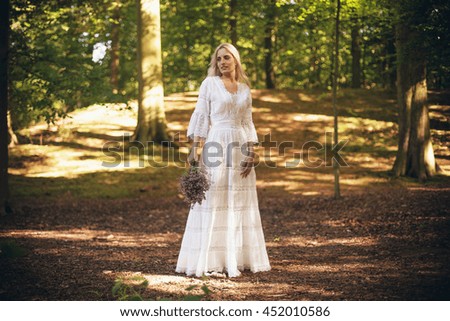 Bride in white dress standing in forest