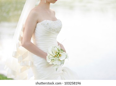 Bride in a white dress in summer green park near the lake - Powered by Shutterstock