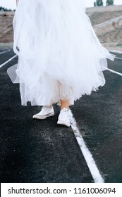 Bride in white sneakers. Lifestyle and casual. Wedding day. Bride in a white dress at the stadium.