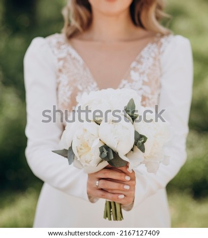 The bride in a white wedding dress is holding a bouquet of white flowers - peonies.. Wedding. Bride and groom. Wedding Dress