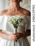The bride in a white wedding dress holds a bouquet of white flowers - callas.. Wedding. Bride and groom. Wedding Dress