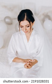 The Bride In A White Wedding Gown Puts A Wedding Ring On Her Finger.