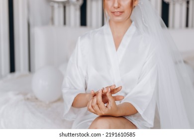 The Bride In A White Wedding Gown Puts A Wedding Ring On Her Finger.