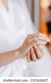 The Bride In A White Wedding Gown Puts A Wedding Ring On Her Finger.