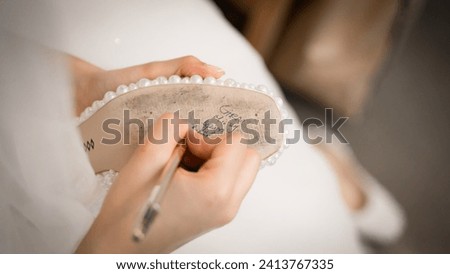 Bride writes under shoe wedding ritual superstition . hand of a bride writing single friends name under her shoe before wedding . Bride writing her shoe with a pencil .
