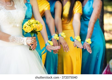 The Bride With A Yellow Bouquet Of Roses And Bridesmaids In Blue And Yellow Dresses