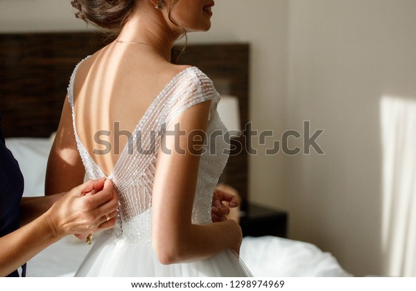 bride zipping up her wedding\
dress