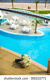 Bride's Bouquet Is Lying Near The Fencing. Its Opposite The Swimming Pool.