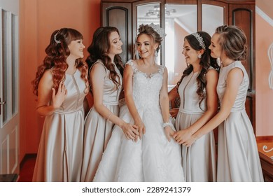 the bride's friend prepares the bride for the wedding day. The bride's friends happily pose with the bride for a photo - Powered by Shutterstock