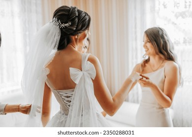 the bride's friend prepares the bride for the wedding day. Bridesmaids help tie the bride's wedding dress before the ceremony.